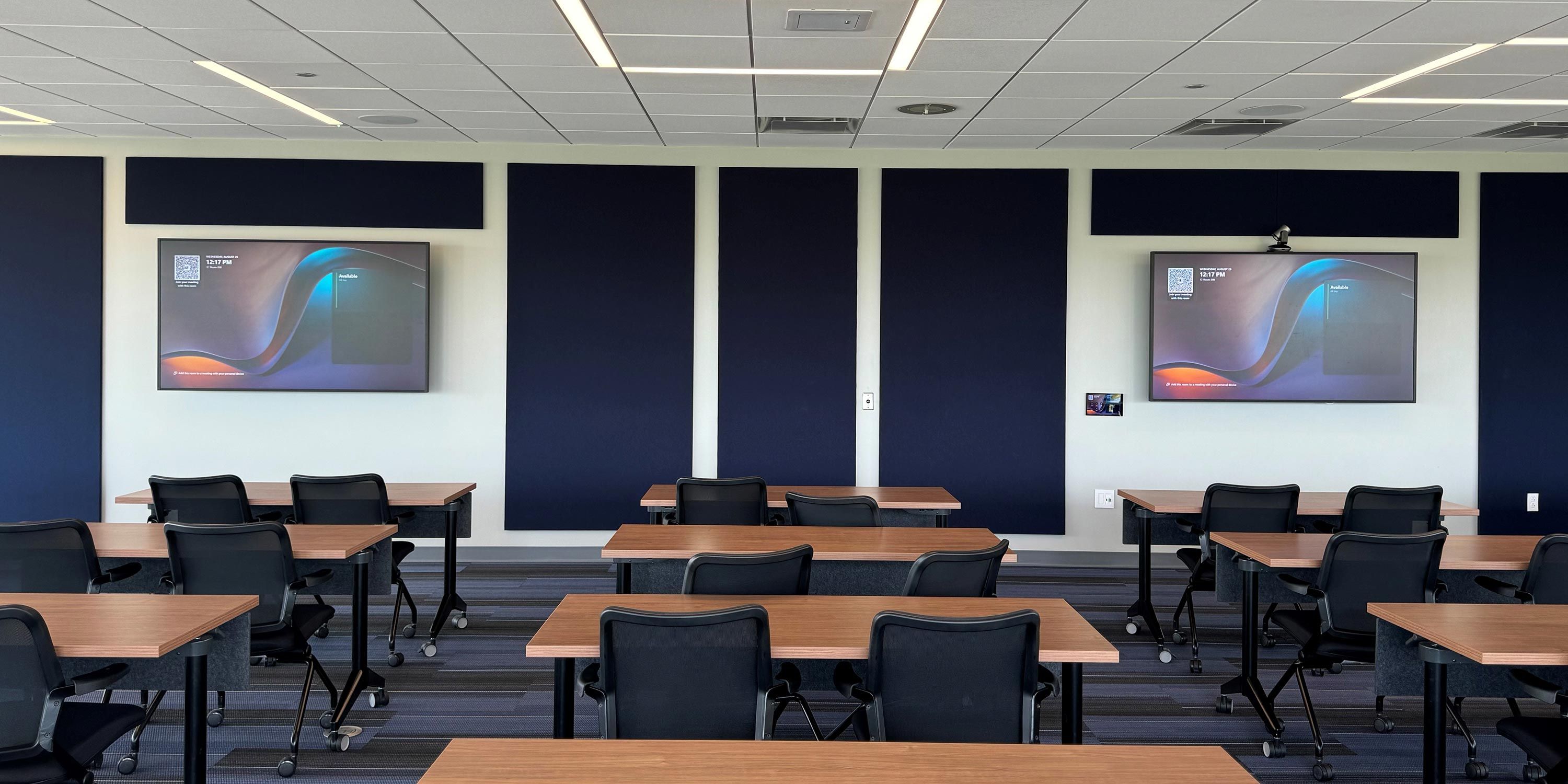 A spacious auditorium-style training room with rows of chairs and a large display screen.