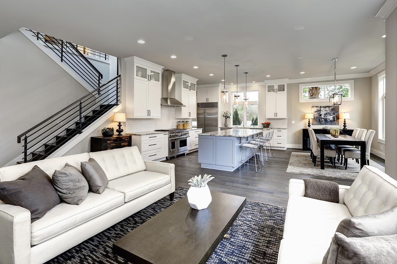 Modern open-plan kitchen and living area with a large island, stylish seating, and a dining table, showcasing integrated home audio.