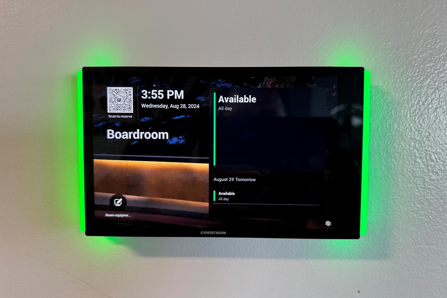 A modern boardroom setup with a central display screen and a touch control panel on a conference table.