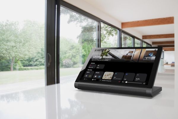 A modern smart home display placed on a sleek white counter, overlooking a room with large windows and garden views.