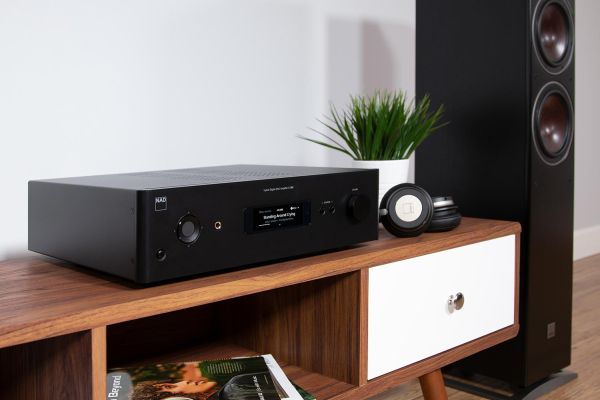 A modern media console with a sleek audio amplifier, headphones, and a large speaker in a clean, contemporary setting.